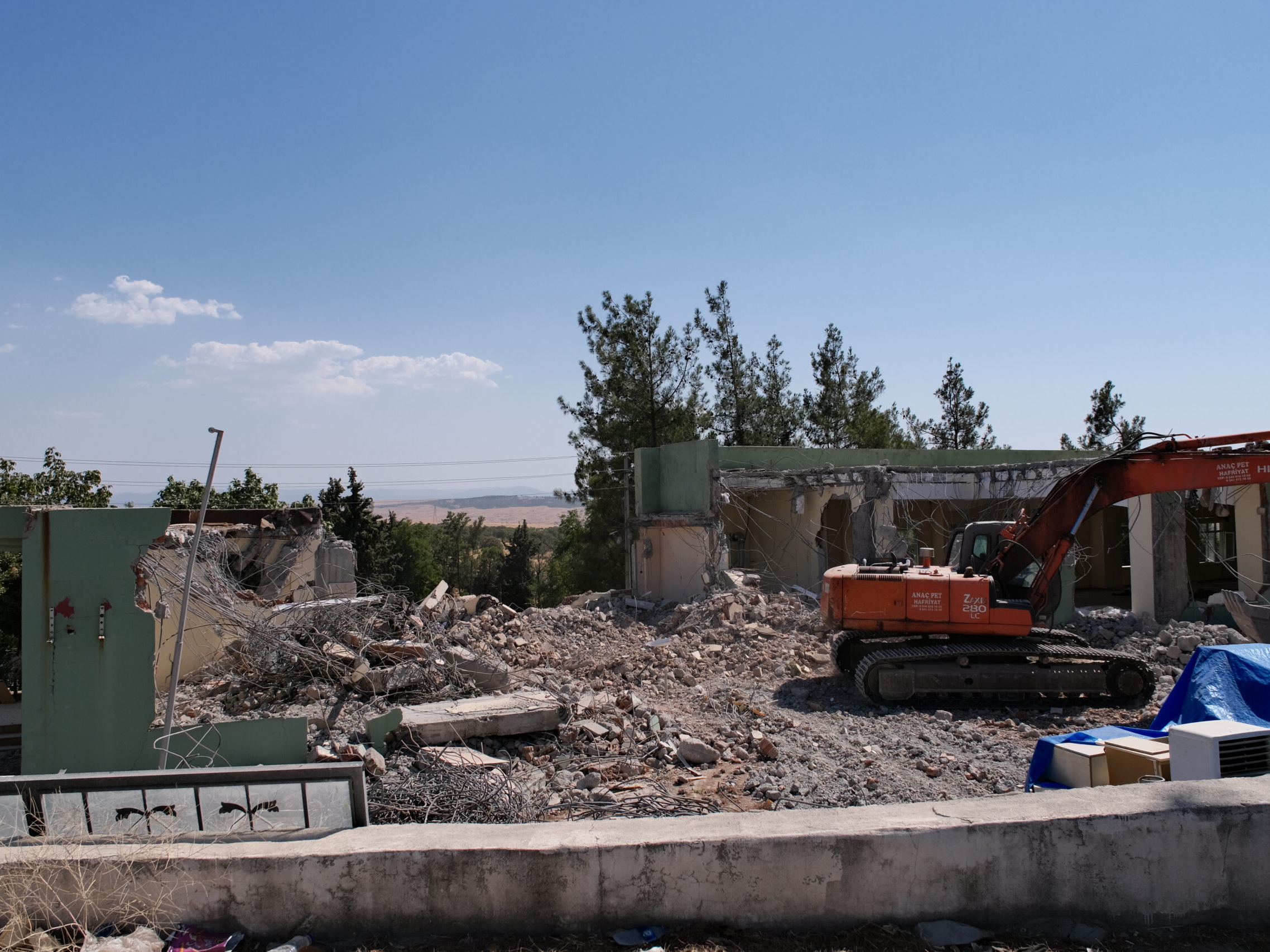 Ein Bagger arbeitet an einem Haus in der Türkei, das durch das Erdbeben eingestürzt ist.