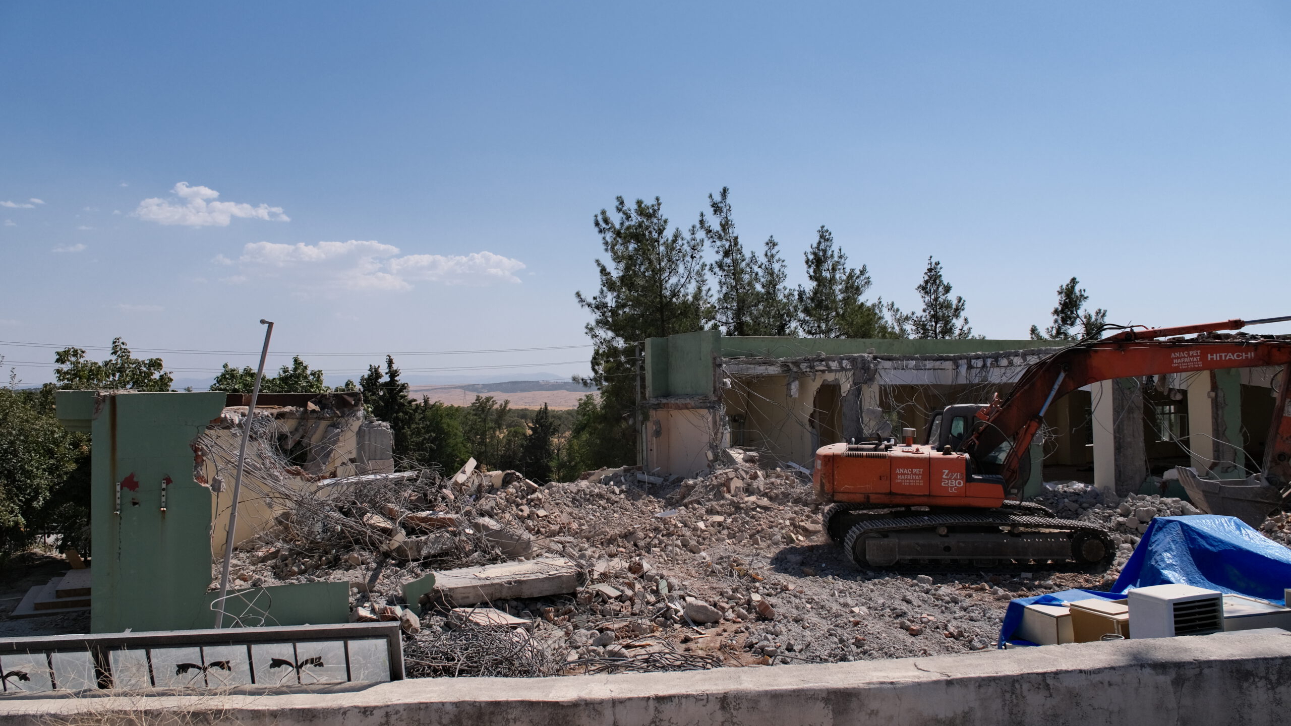 Ein Bagger arbeitet an einem Haus in der Türkei, das durch das Erdbeben eingestürzt ist.